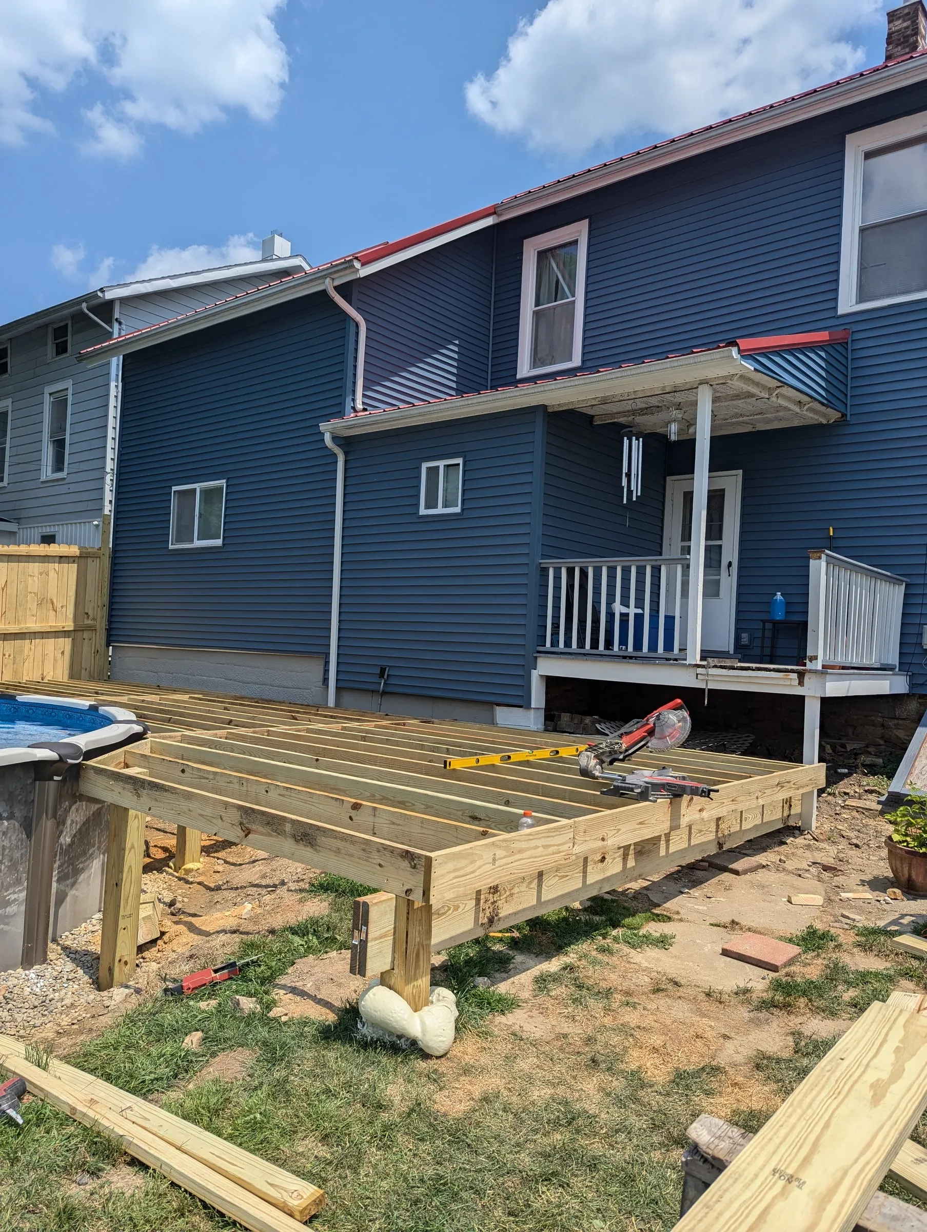 Deck frame of pressure-treated joists on posts next to the pool