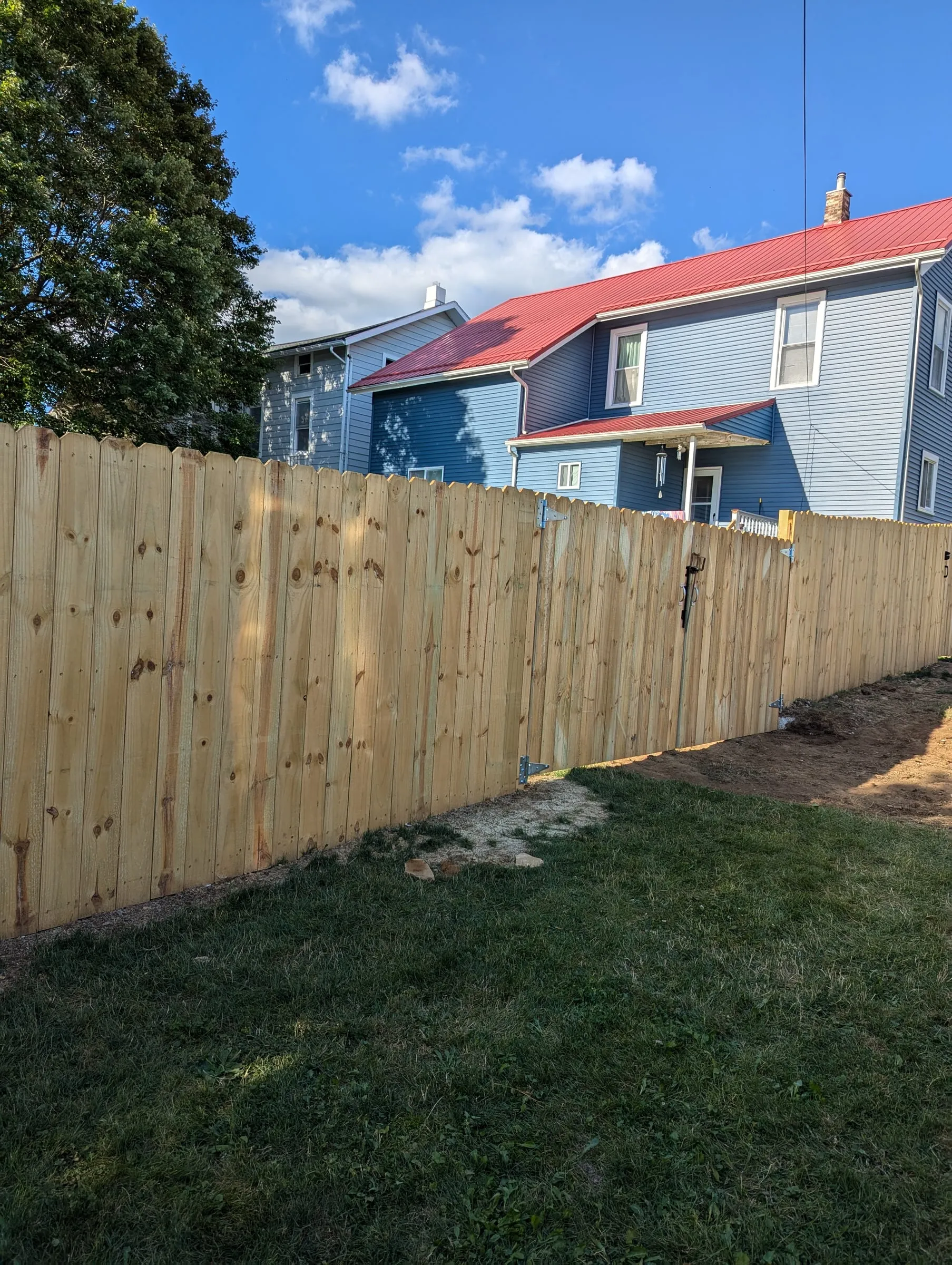Wood privacy fence with a hinged gate behind a blue house