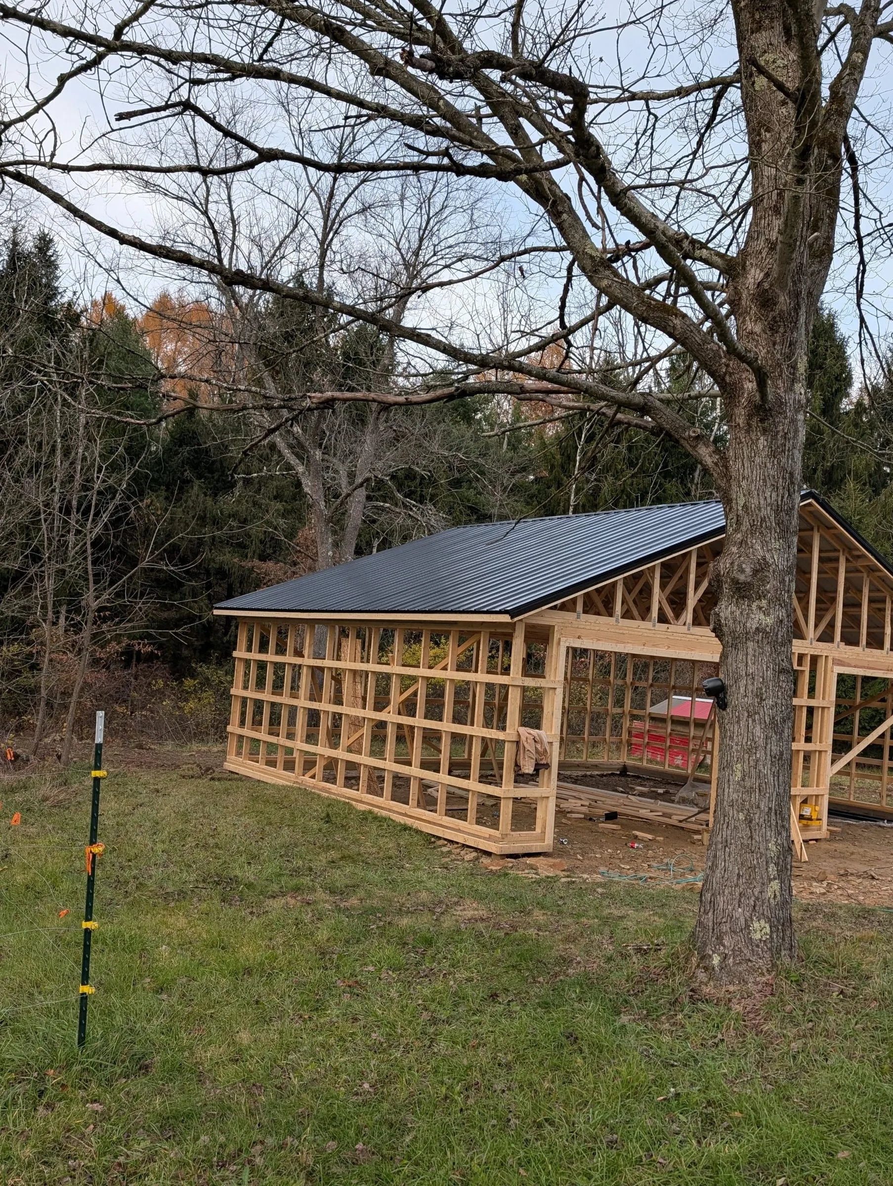 Garage frame with a black metal roof installed and open walls