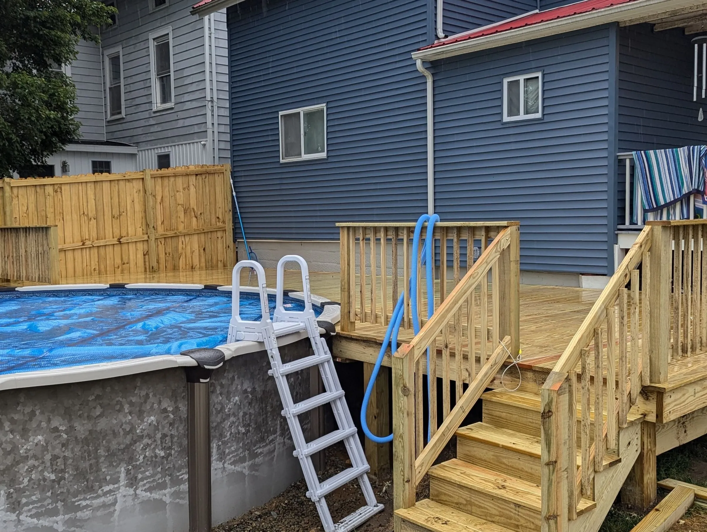 Deck stairs and railings leading down from the back porch beside the pool