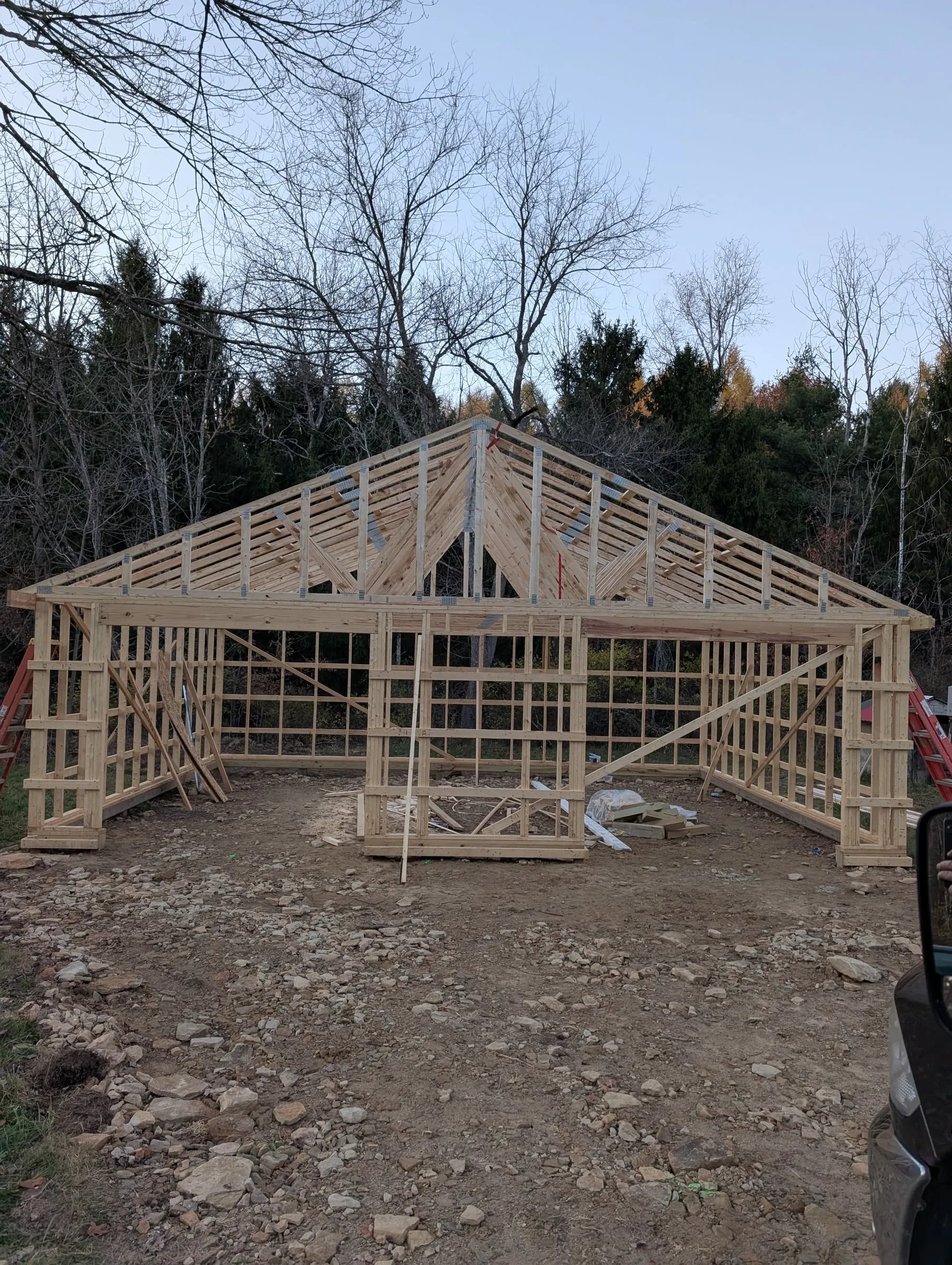 Garage wall framing with roof trusses set, in a wooded clearing